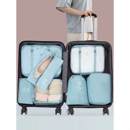 Pessoa organizando mala de viagem preta com organizadores azuis claros para roupas e sapatos