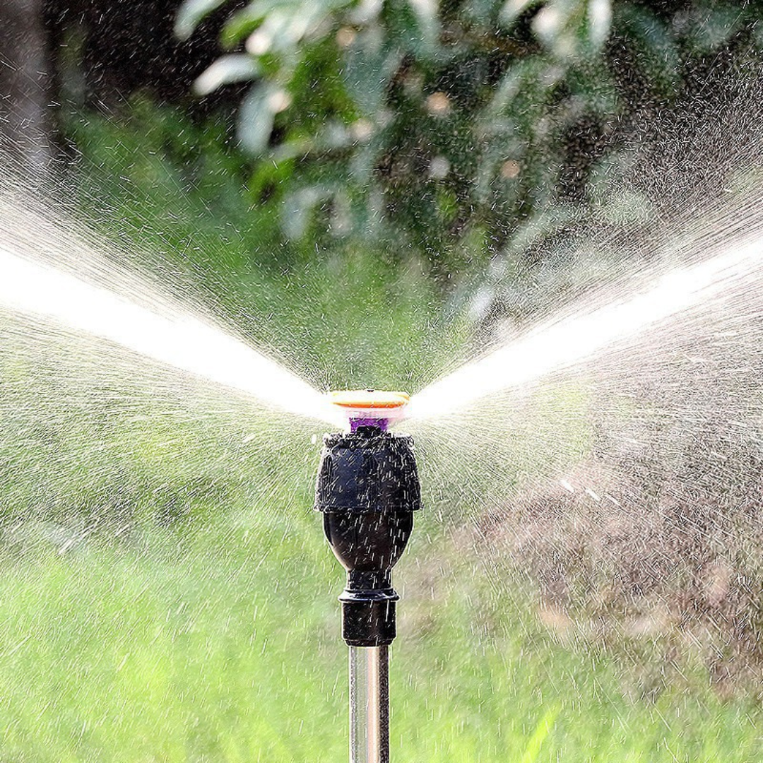 Aspersor de jardim preto em funcionamento borrifando água em ambiente verde externo