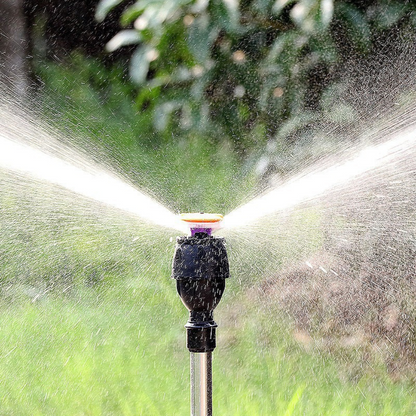 Aspersor de jardim preto em funcionamento borrifando água em ambiente verde externo