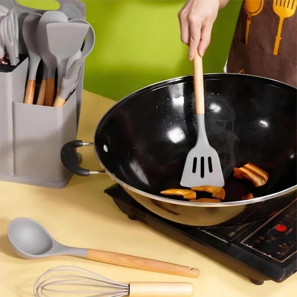 Utensílios de cozinha de silicone com cabo de madeira sendo usados para mexer cogumelos em wok preta sobre fogão elétrico